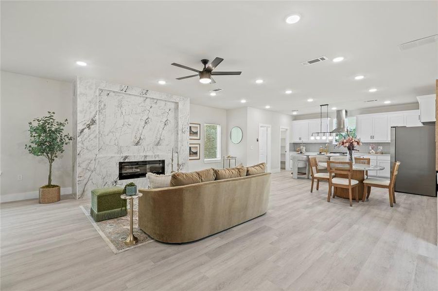 Living area featuring light wood-style flooring, ceiling fan, a high end fireplace, and recessed lighting Living area featuring light wood-style flooring, ceiling fan, a high end fireplace, and recessed lighting