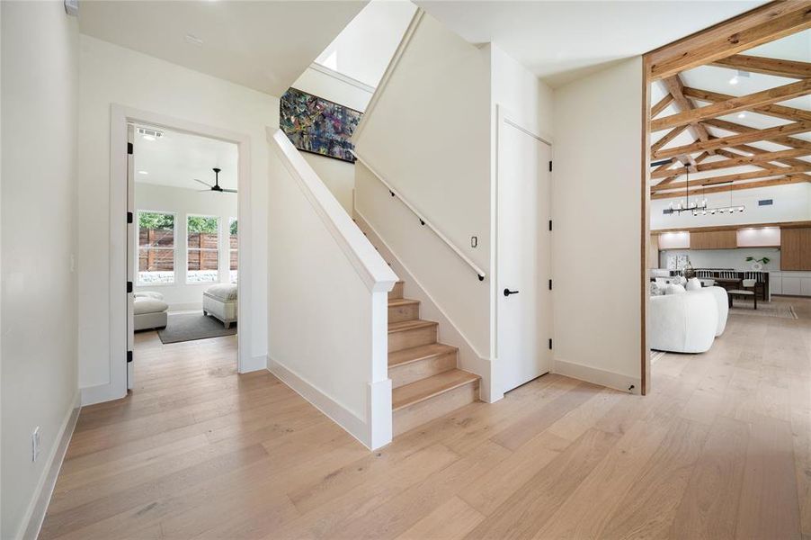 Stairway with beam ceiling, ceiling fan, and light wood-type flooring