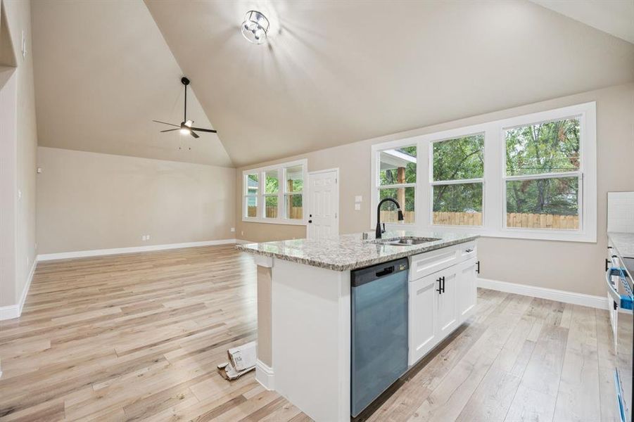 Kitchen with white cabinets, light stone countertops, a kitchen island with sink, dishwashing machine, and stainless steel range oven Kitchen with white cabinets, light stone countertops, a kitchen island with sink, dishwashing machine, and stainless steel range oven