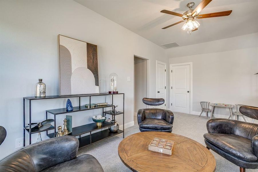 Carpeted living area featuring baseboards and a ceiling fan