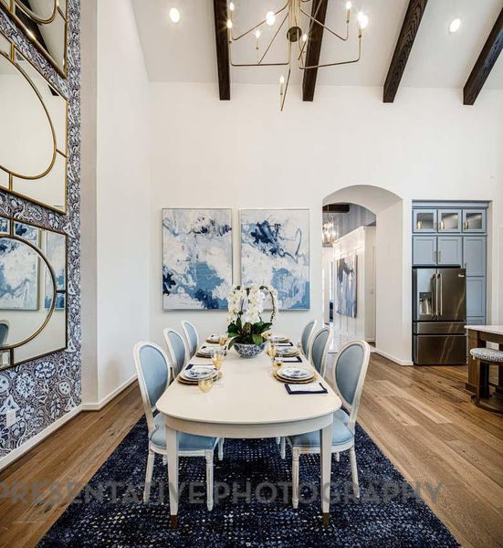 Dining area with a chandelier, arched walkways, wood finished floors, beamed ceiling, and wallpapered walls Dining area with a chandelier, arched walkways, wood finished floors, beamed ceiling, and wallpapered walls