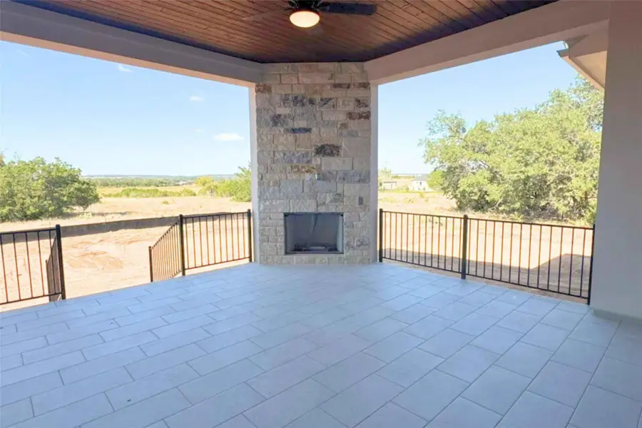 View of patio / terrace featuring an outdoor stone fireplace and ceiling fan