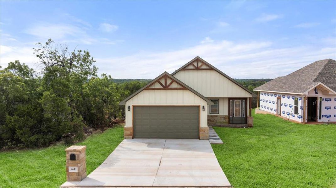 View of front of house with a front lawn, concrete driveway, stone siding, and an attached garage View of front of house with a front lawn, concrete driveway, stone siding, and an attached garage