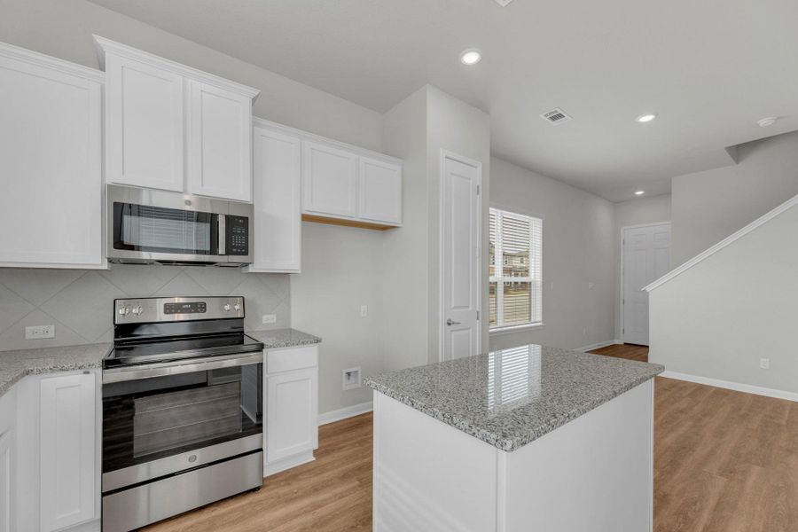 Kitchen with appliances with stainless steel finishes, light stone countertops, light wood-type flooring, and recessed lighting
