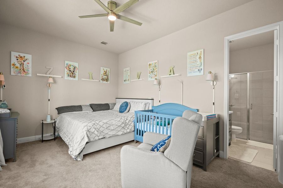 Bedroom with a ceiling fan, carpet floors, and ensuite bath Bedroom with a ceiling fan, carpet floors, and ensuite bath