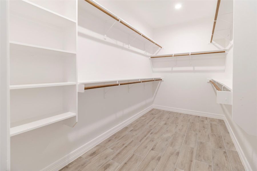 Shelving and hanging space stretch around the walk-in closet instead of stopping at a single rod. Shelving and hanging space stretch around the walk-in closet instead of stopping at a single rod.