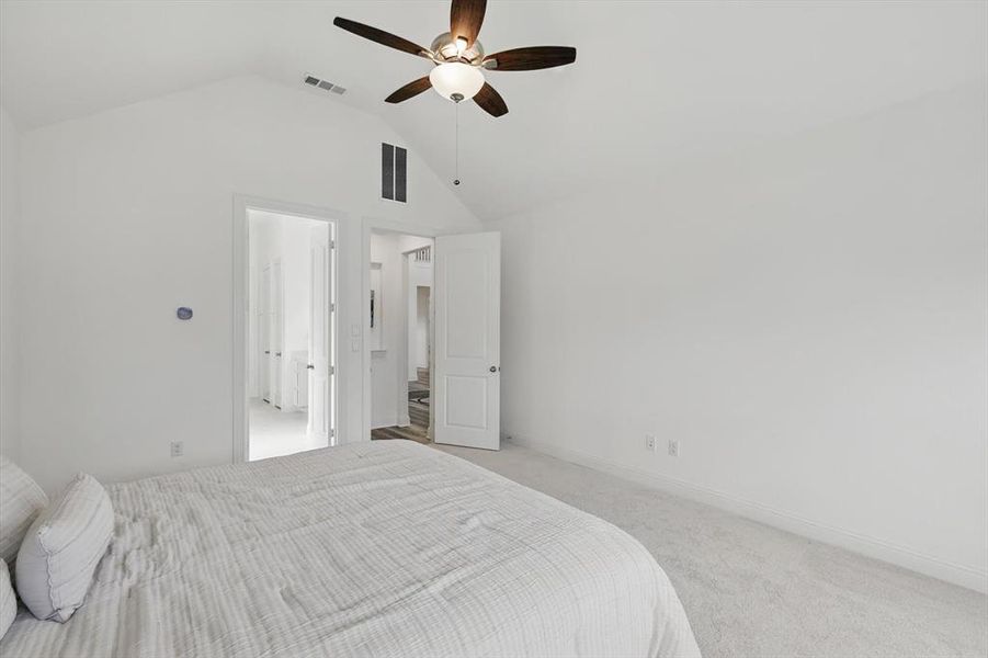 Carpeted bedroom with vaulted ceiling and a ceiling fan
