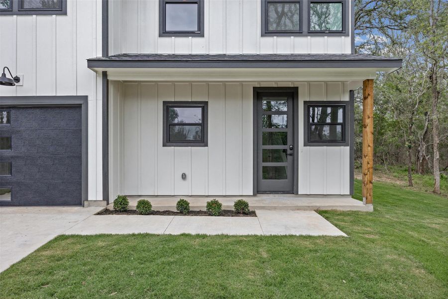 Contemporary exterior featuring vertical white siding, dark trim, and a covered porch with a natural wood post Contemporary exterior featuring vertical white siding, dark trim, and a covered porch with a natural wood post