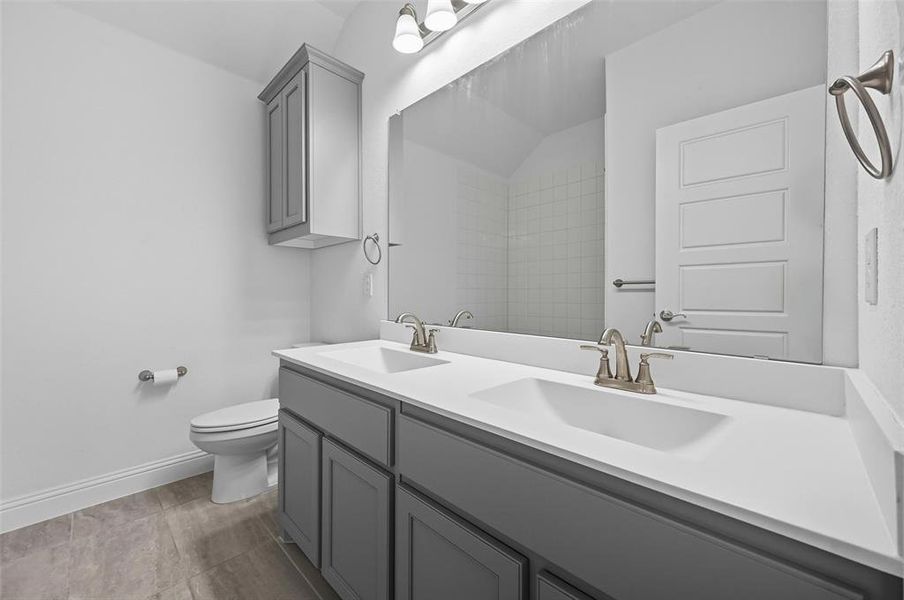 Full bath featuring double vanity and toilet