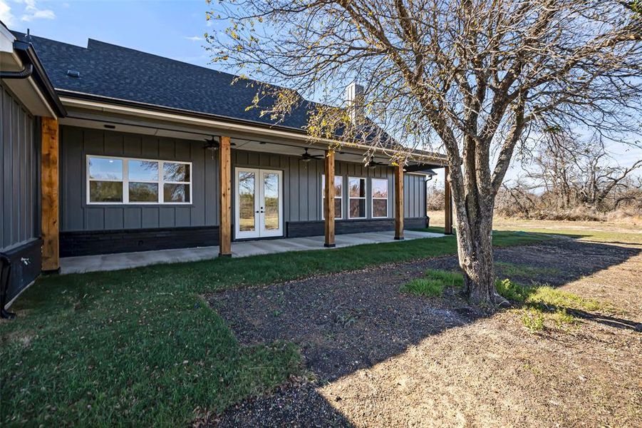 Rear view of property with a lawn, ceiling fan, a patio area, and french doors