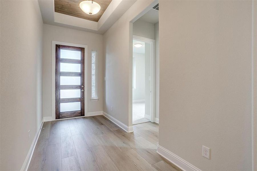 Foyer featuring light wood-type flooring and a tray ceiling