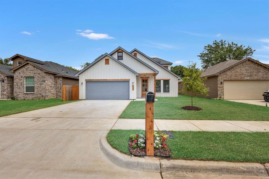 View of front of property featuring a garage and a front lawn