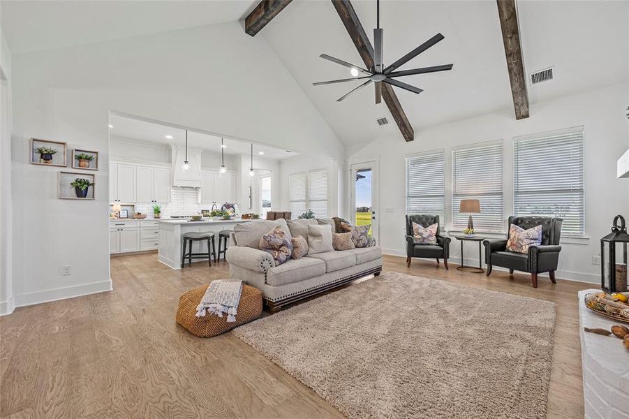 Living room with ceiling fan, beamed ceiling, light hardwood / wood-style flooring, and high vaulted ceiling