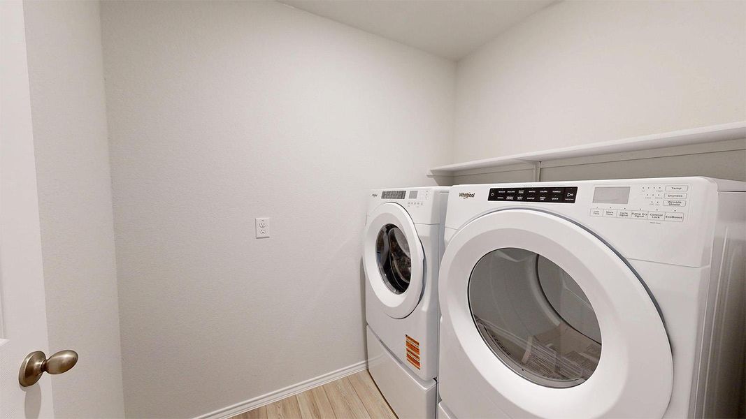 Functional laundry room featuring a washer, dryer, and convenient shelving for storage.