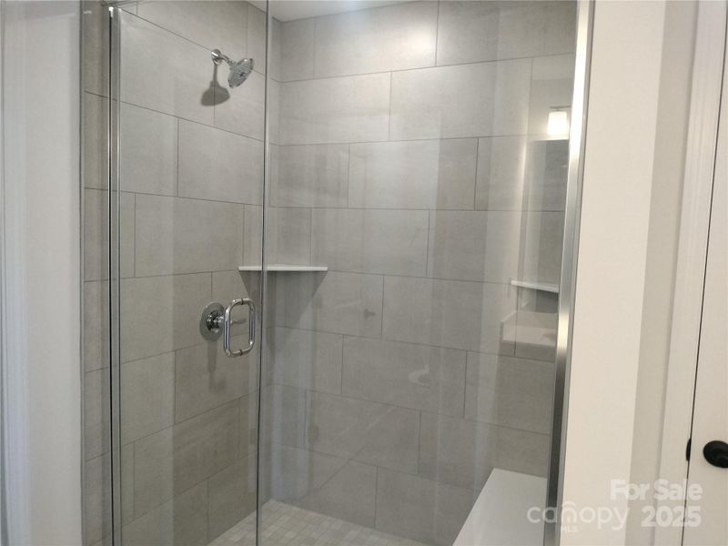 Floor to Ceiling Tile on the walls and floor of this large 5' shower! Two corner shelves give plenty of room for everyone's supplies. Representative Photo