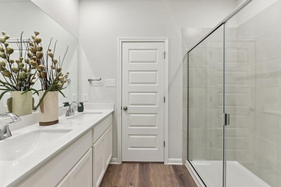Full bath featuring a shower stall, wood finished floors, and double vanity