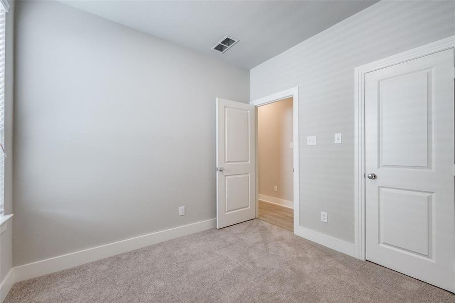 Unfurnished bedroom featuring light colored carpet and baseboards