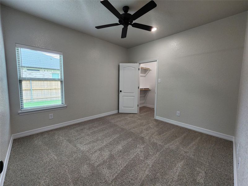 A well-lit room with plush carpet flooring and a spacious walk-in closet. A well-lit room with plush carpet flooring and a spacious walk-in closet.