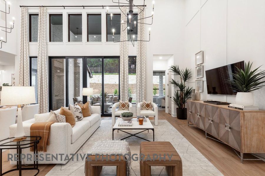 Living room featuring a high ceiling, light wood-type flooring, and a chandelier Living room featuring a high ceiling, light wood-type flooring, and a chandelier