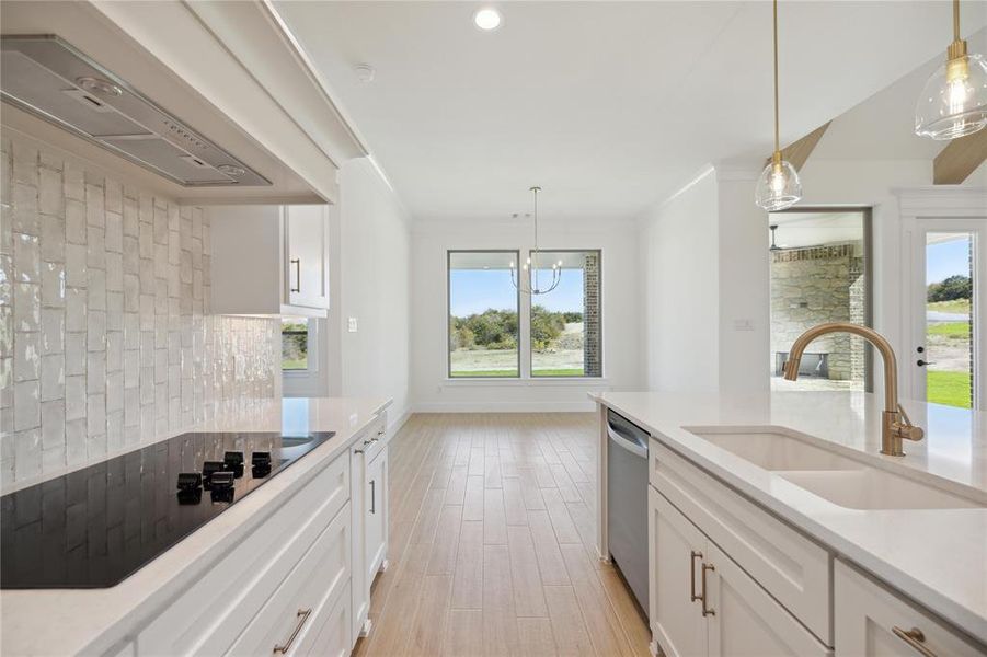 Kitchen with white cabinets, a wealth of natural light, premium range hood, and black electric stovetop