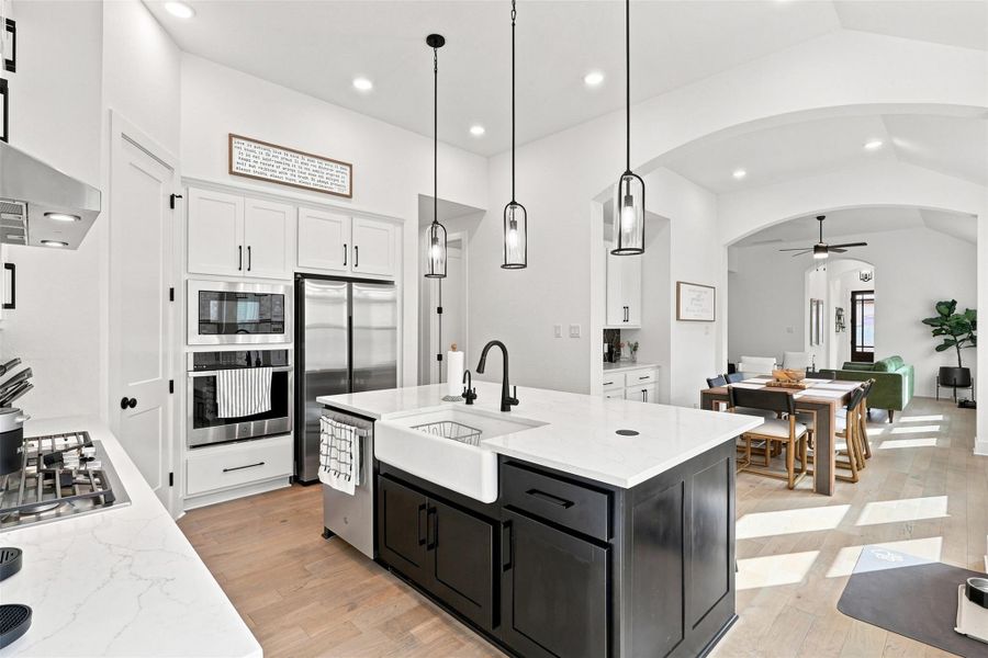 Arched doorways frame a luminous open kitchen with a center island and hardwood floors.