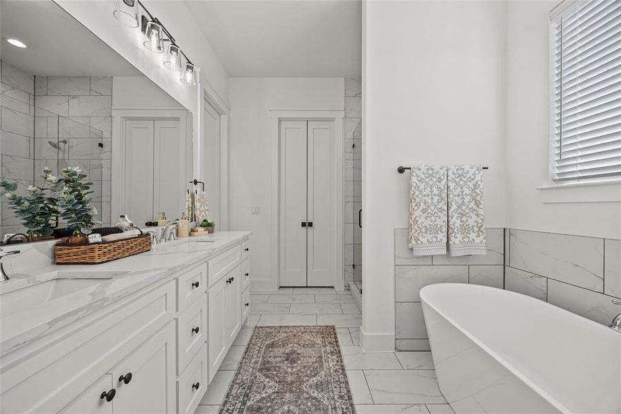 Bathroom featuring a healthy amount of sunlight, tile patterned floors, a tub to relax in, and vanity