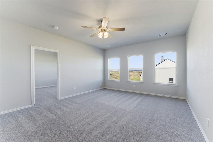 Carpeted empty room featuring baseboards and a ceiling fan
