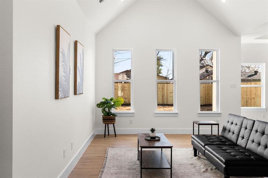 Sitting room featuring high vaulted ceiling, light wood-type flooring, and baseboards