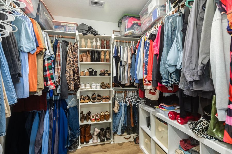 Spacious walk-in closet with ample hanging space, shelving for shoes, and storage bins, offering great organization for clothing and accessories.