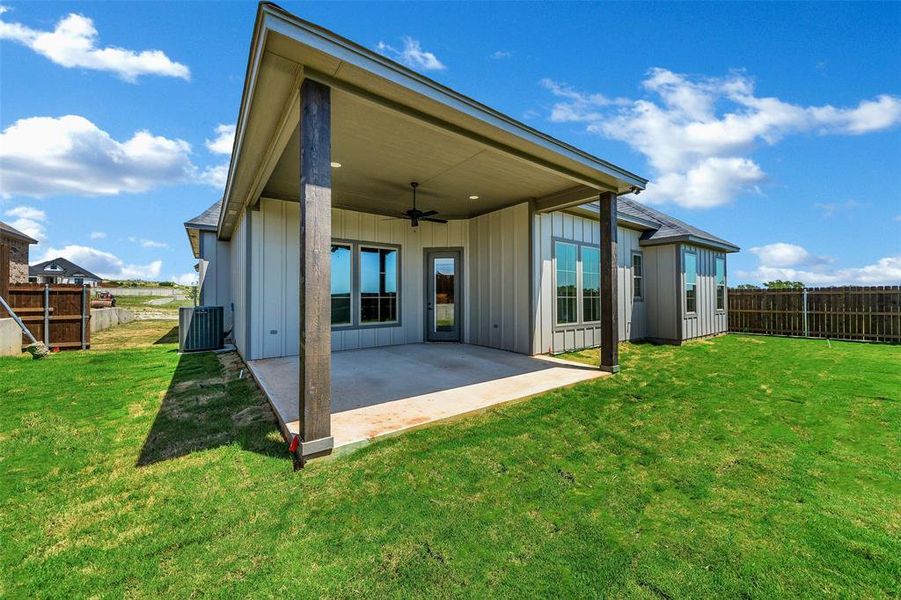 Rear view of property featuring a ceiling fan, a patio, board and batten siding, and a fenced backyard