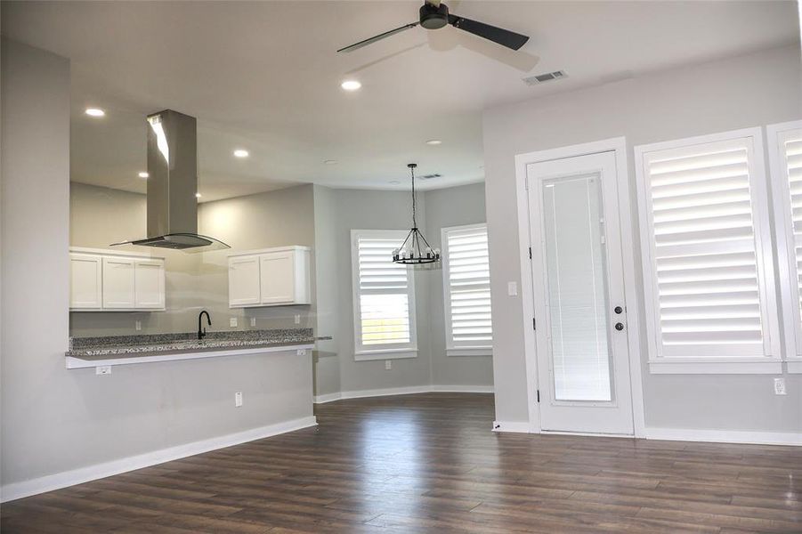 Kitchen featuring dark wood-style floors, island exhaust hood, white cabinetry, recessed lighting, and a chandelier