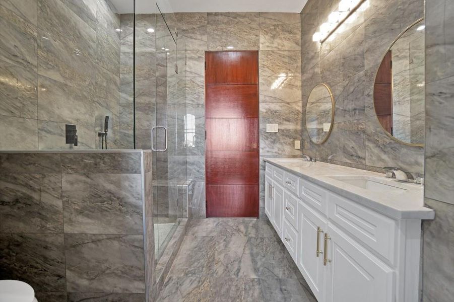 Bathroom with tile walls, vanity, and a shower with shower door