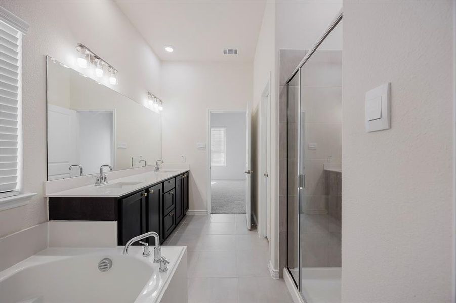 Bathroom featuring tile patterned floors, separate shower and tub, and vanity