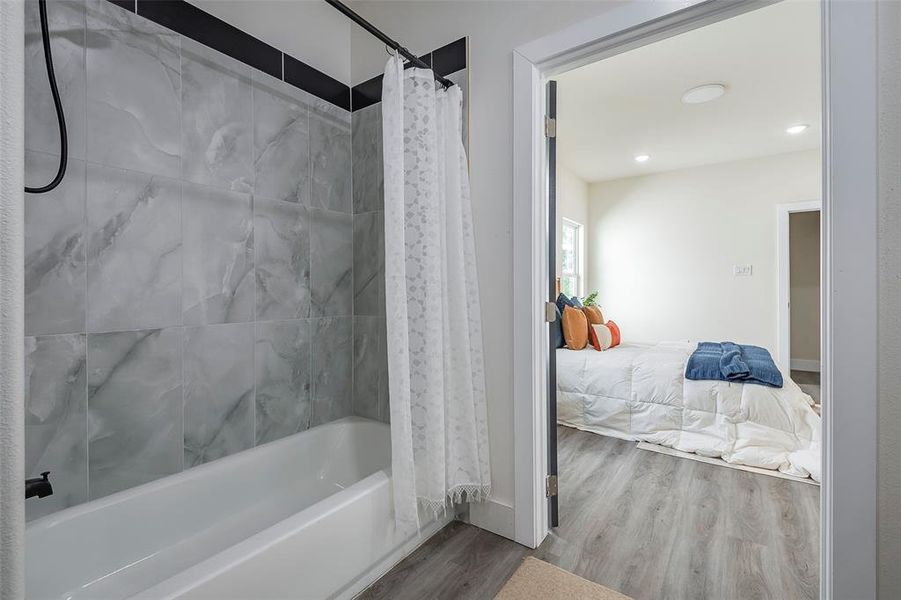 Bathroom with wood-type flooring and shower / bathtub combination with curtain