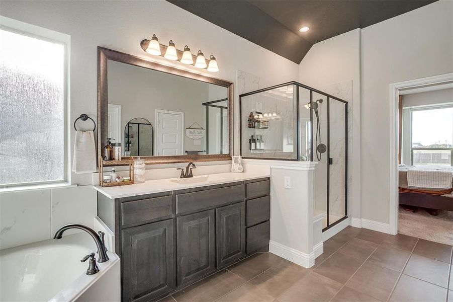 Bathroom with tile patterned floors, vanity, plus walk in shower, and vaulted ceiling