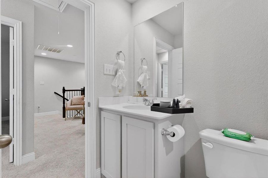 Bathroom featuring a white vanity with a single sink, an integrated mirror, and a toilet