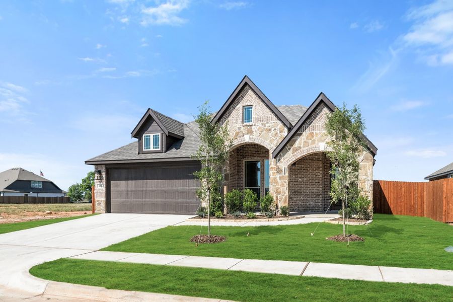 Single-story home with brick and stone exterior, two-car garage, arched entry, and green front lawn Single-story home with brick and stone exterior, two-car garage, arched entry, and green front lawn