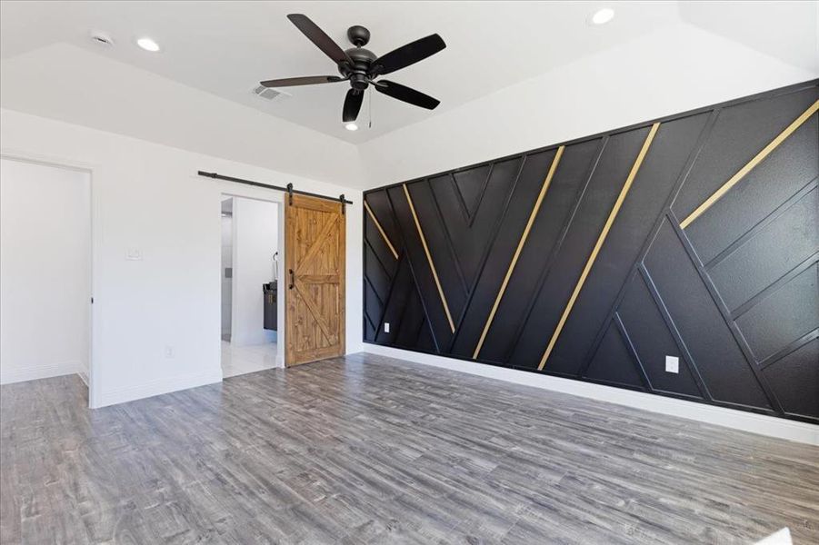 Spare room with a barn door, visible vents, a ceiling fan, wood finished floors, and recessed lighting