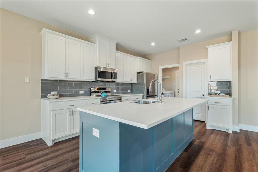 Kitchen featuring a kitchen island with sink, white cabinetry, dark wood-type flooring, and appliances with stainless steel finishes Kitchen featuring a kitchen island with sink, white cabinetry, dark wood-type flooring, and appliances with stainless steel finishes