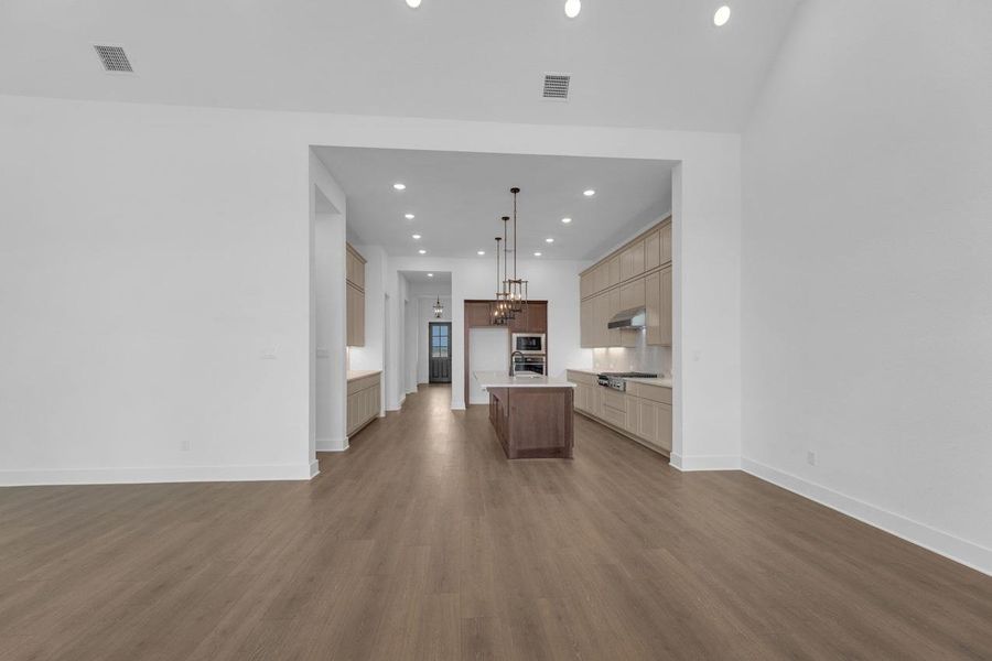 Kitchen with open floor plan, recessed lighting, an island with sink, dark wood-style flooring, and hanging light fixtures Kitchen with open floor plan, recessed lighting, an island with sink, dark wood-style flooring, and hanging light fixtures