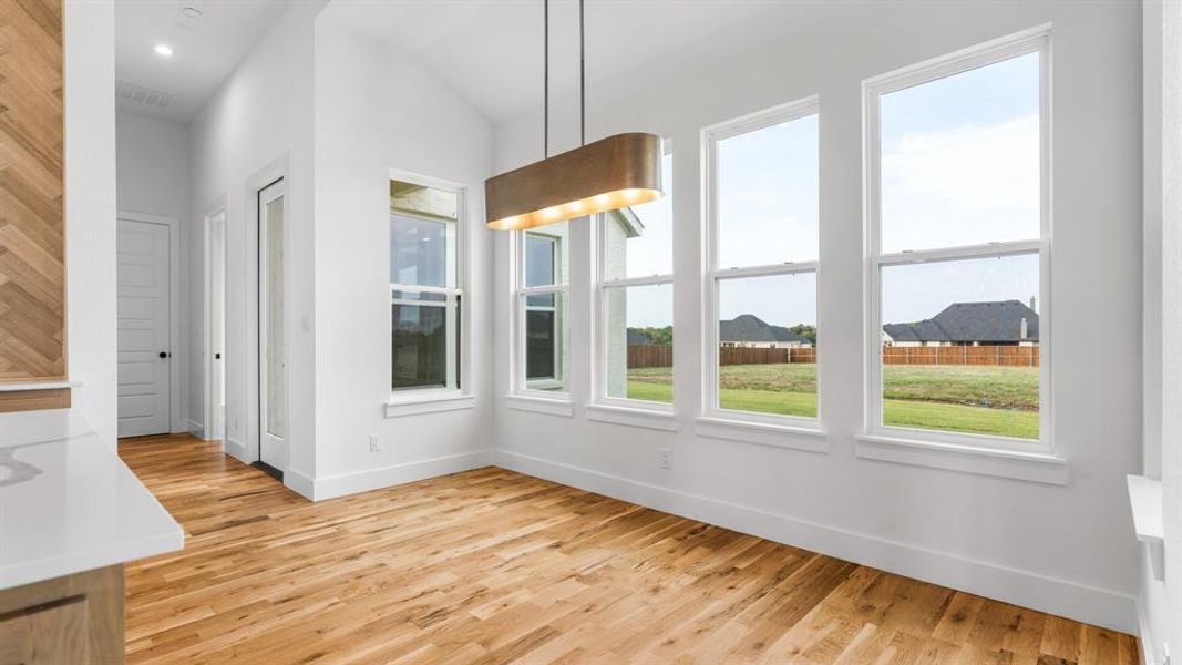 Unfurnished dining area featuring light hardwood / wood-style flooring and lofted ceiling