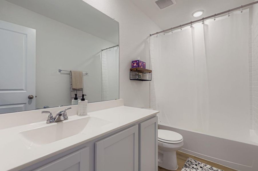 Full bath featuring shower / tub combo with curtain, vanity, and dark wood-style flooring