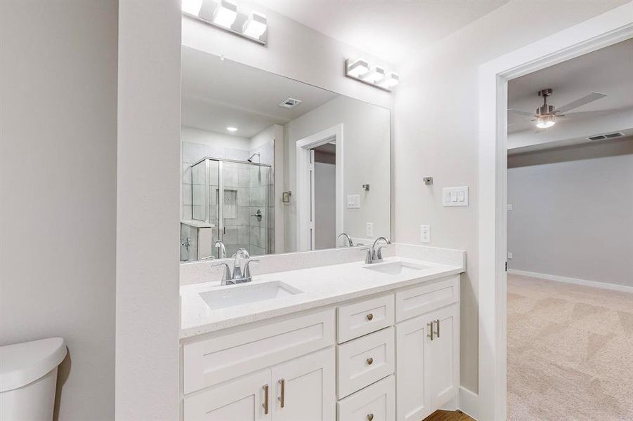 Bathroom featuring vanity, toilet, walk in shower, and ceiling fan