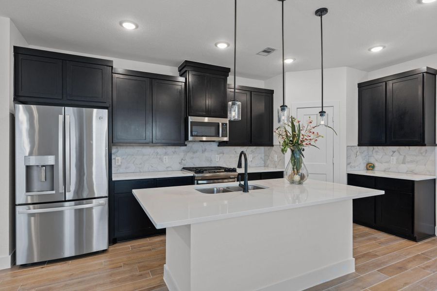 Great view of the spacious island kitchen featuring a large center island, breakfast bar, lots of storage and upgraded stove cooktop.