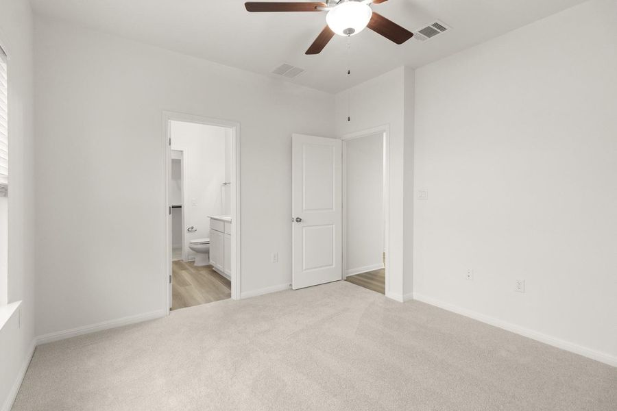 Bright room featuring light-colored carpeting, white walls, and a ceiling fan with a light fixture