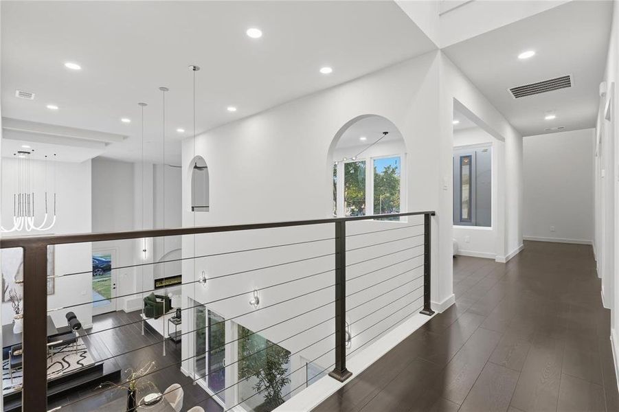 Upper-level hallway featuring dark wood-finish flooring, recessed lighting, and a contemporary cable railing system