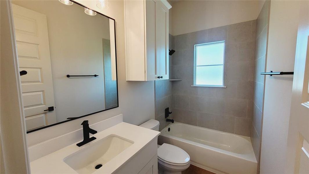 Bathroom featuring a white vanity with an integrated sink, matte black faucet, and a large framed mirror