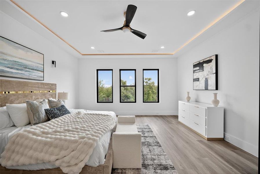Bedroom featuring light wood finished floors, recessed lighting, a ceiling fan, and a raised ceiling