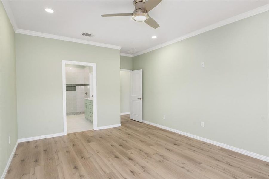 Unfurnished bedroom featuring a spacious closet, light hardwood / wood-style floors, ornamental molding, and ceiling fan