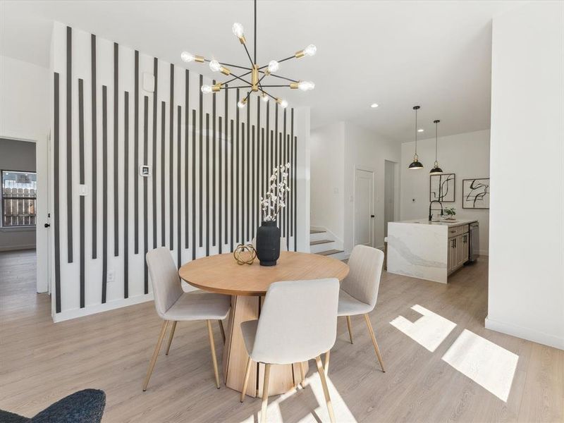 Dining room featuring light wood-style floors, stairs, baseboards, and a chandelier